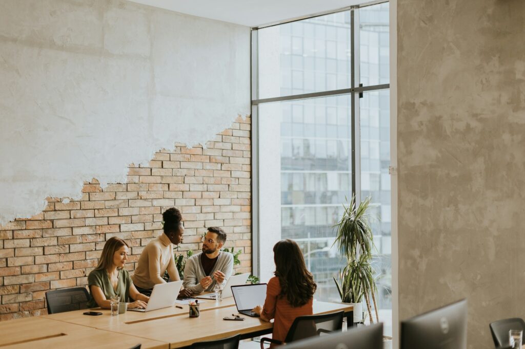 Young multiethnic startup team working by the brick wall in the industrial style office